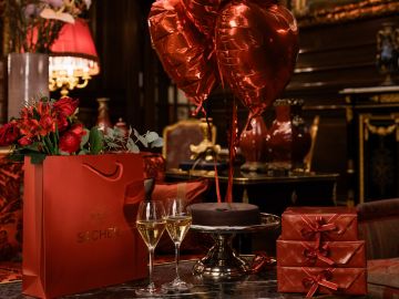 Romantisches Geschenkarrangement im Hotel Sacher mit Sacher-Torte, Champagner, roten Ballons und eleganter Tischdekoration
