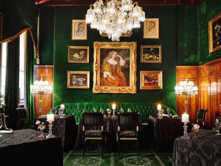 Ein eleganter Speisesaal mit üppigem Interieur, smaragdgrünem Dekor, Kristalllüstern und klassisch gedeckten Tischen