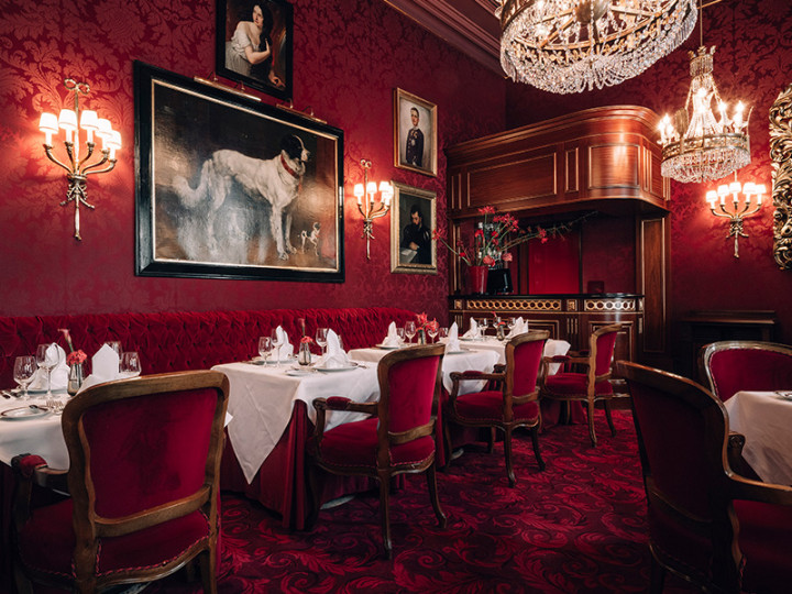 sumptuously laid table in the red and gold ambience of the Sacher restaurant, with sparkling chandeliers and historical paintings