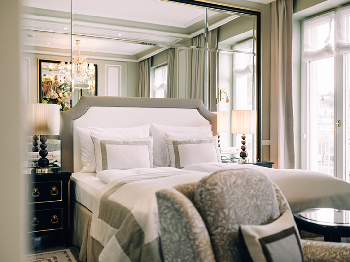 Elegant, bright hotel room with elegant furnishings, large bed, mirrored wall and stylish lamps